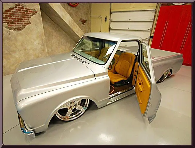 Classic silver pickup truck with custom wheels and open door revealing tan interior.
