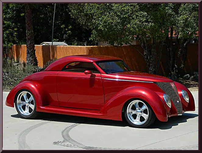 Sleek red vintage-style custom car parked outdoors.