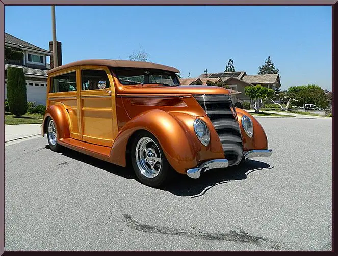 Classic wooden station wagon car in shiny orange paint.