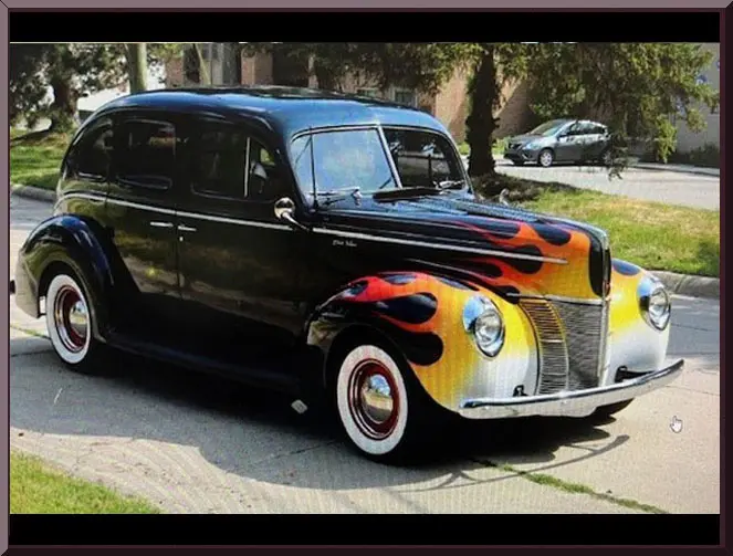 Classic black vintage car with vibrant flame decals on the front.