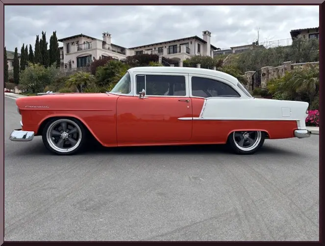 Classic red and white vintage car parked on a suburban street.