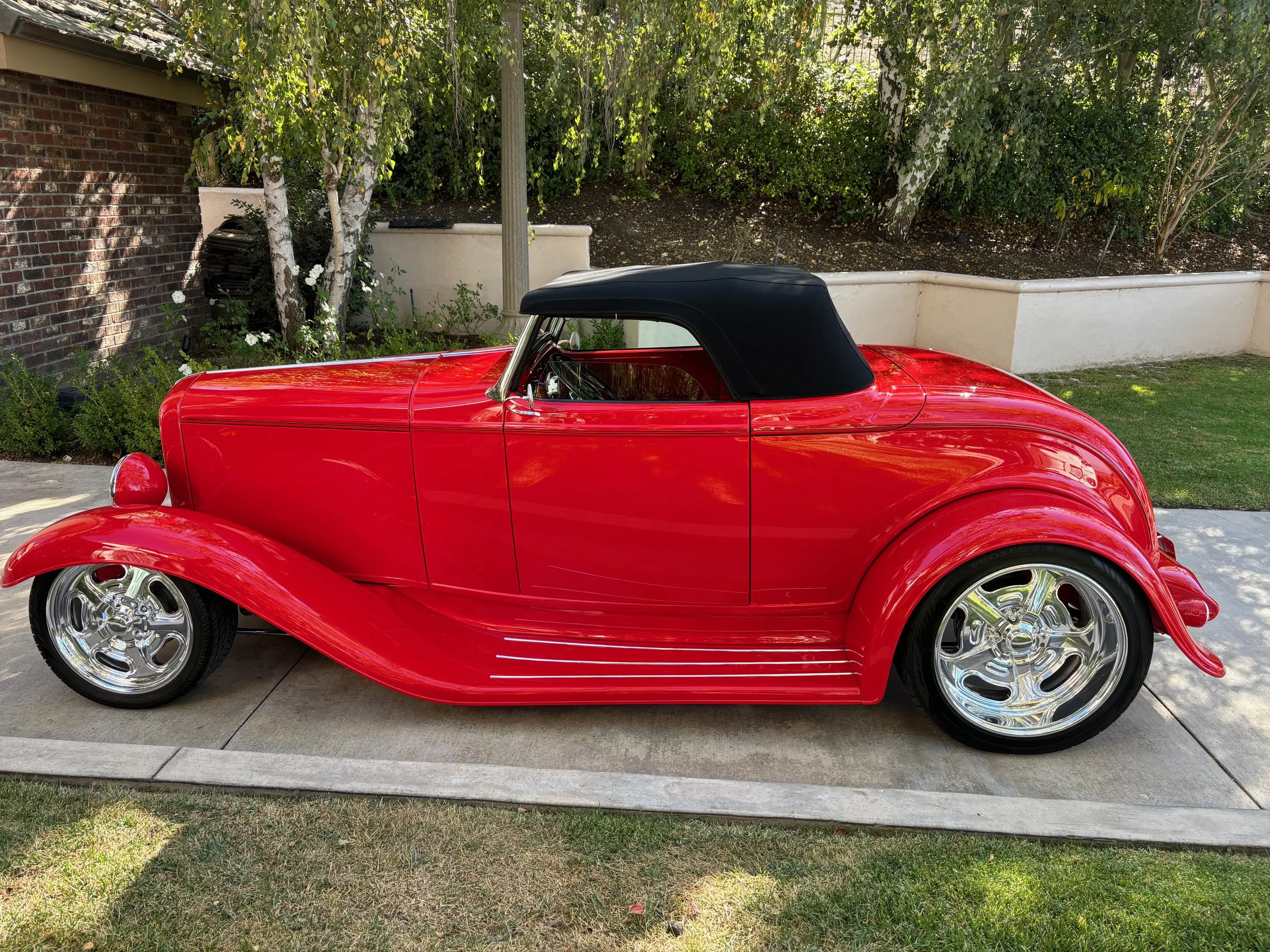 Classic red convertible car with a black soft top and shiny chrome wheels.