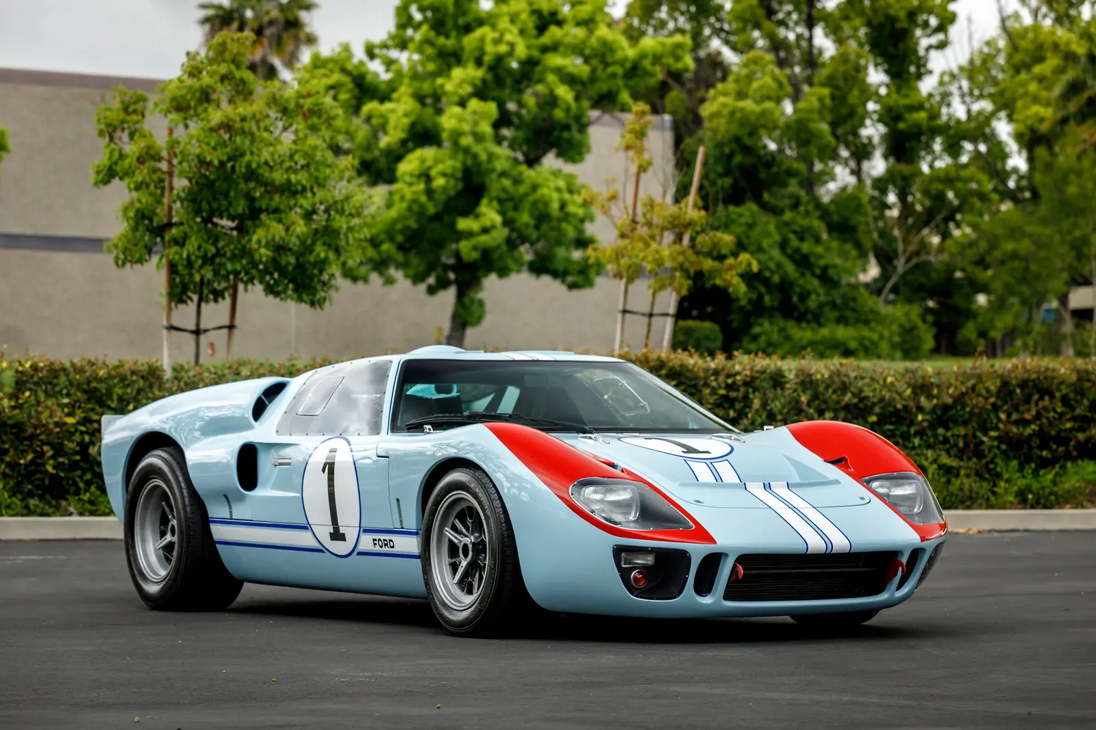 Classic silver race car with red and blue stripes parked outdoors.
