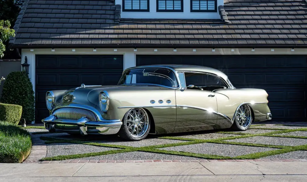 Classic vintage car parked on a driveway in front of a house.