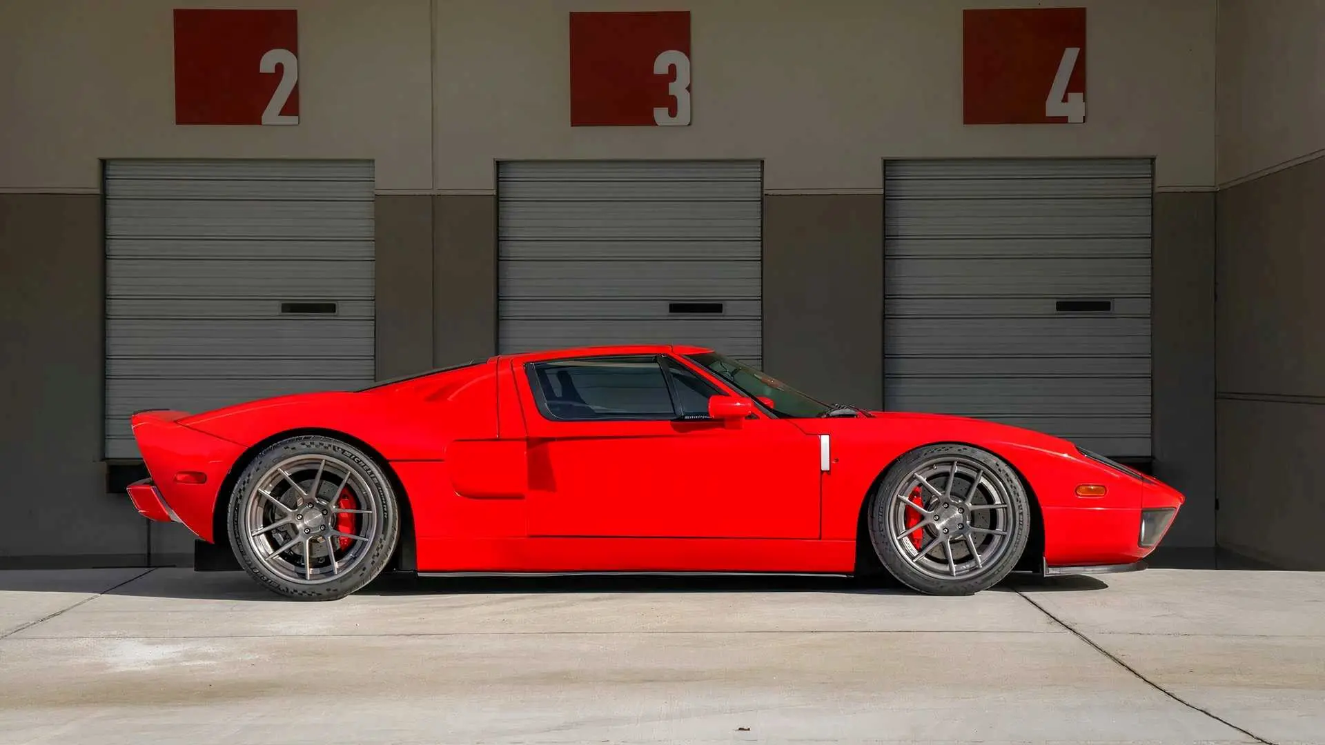 Red sports car parked in front of garage doors.