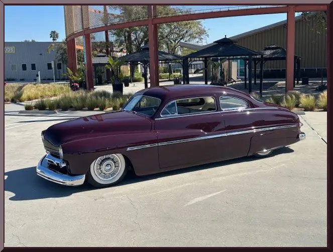 Classic maroon vintage car parked on a sunny day.