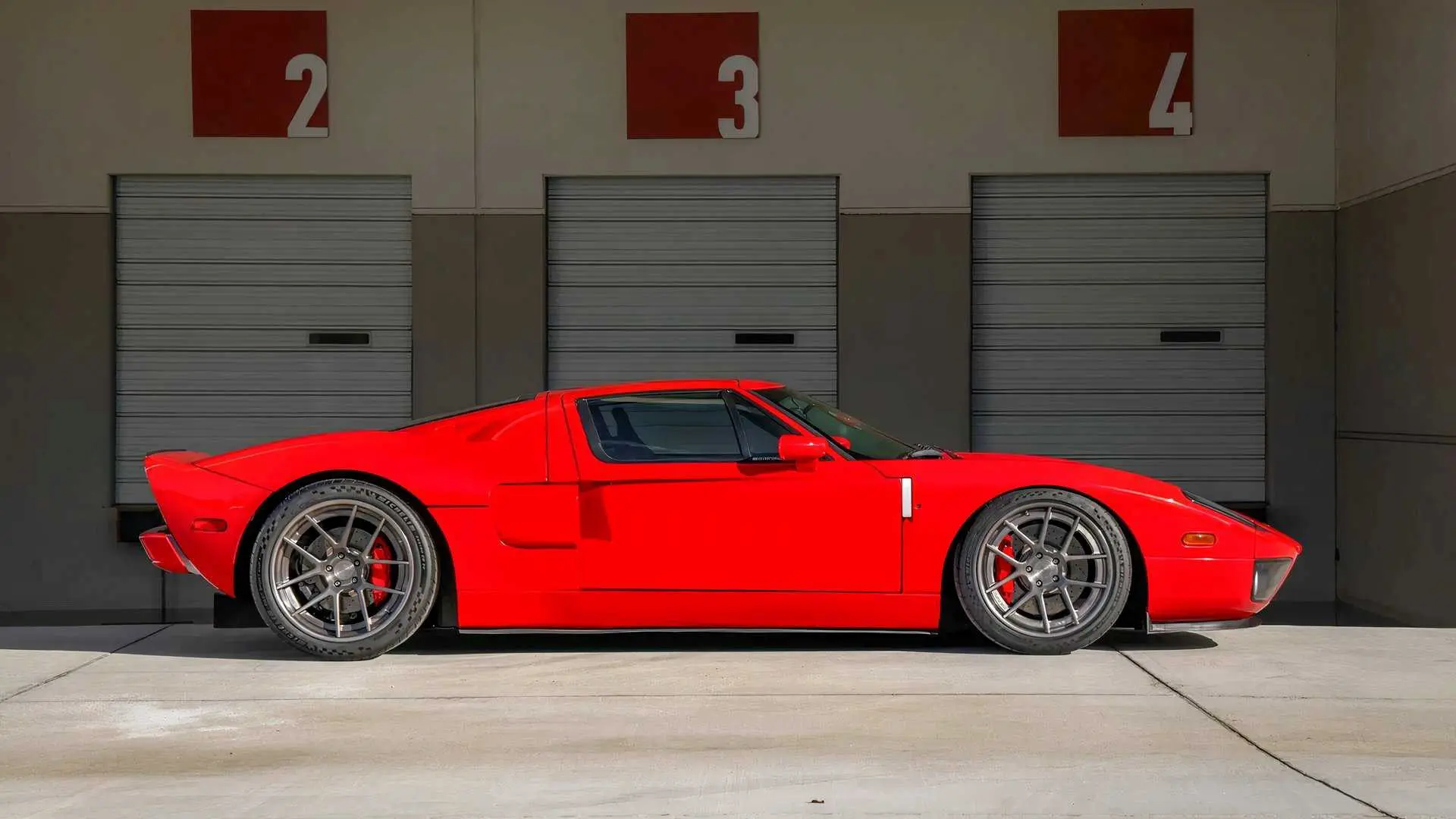 Red sports car parked in front of garage doors.