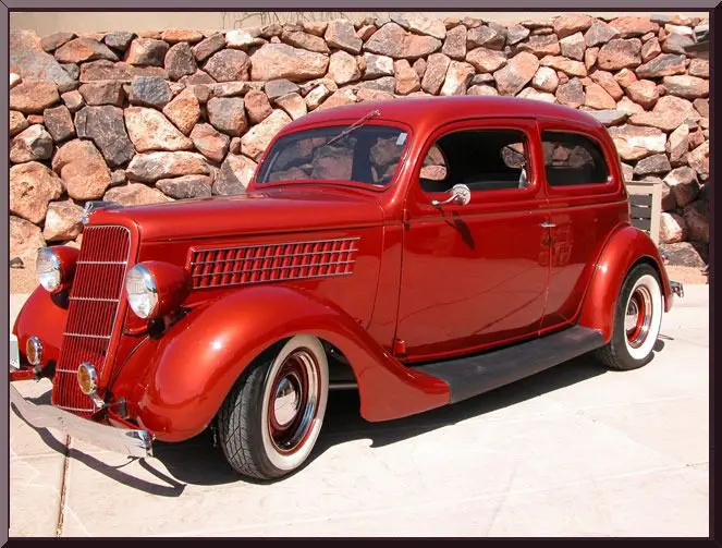 Red vintage car in front of stone wall