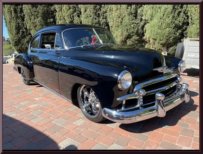 Classic black 1950s car on brick driveway