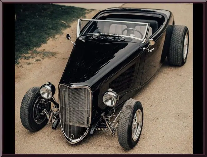 Vintage black hot rod on dirt road.