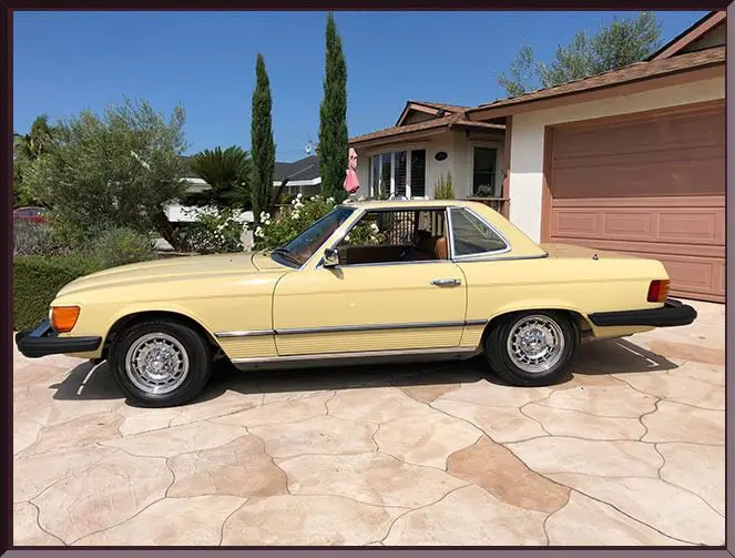 Vintage yellow car parked in driveway