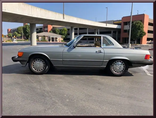 Silver convertible parked near concrete structure.