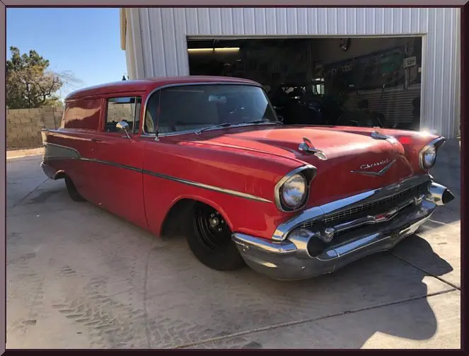 Red classic Chevy panel delivery parked by garage
