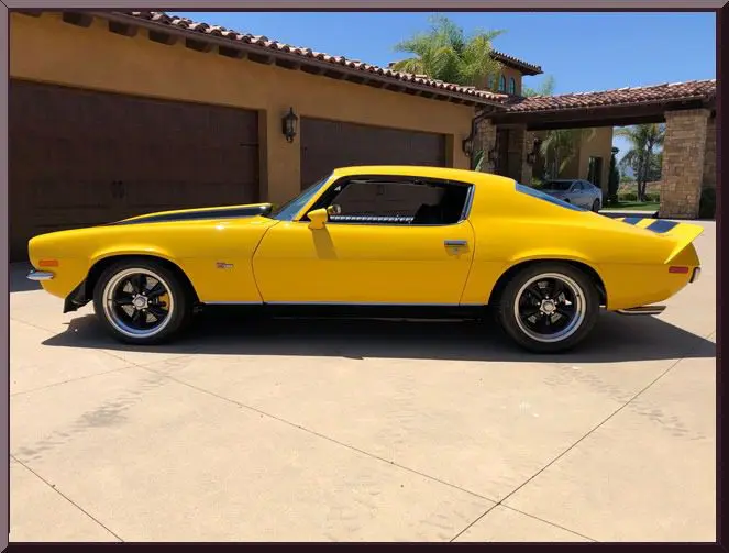 Vintage yellow car near a garage.