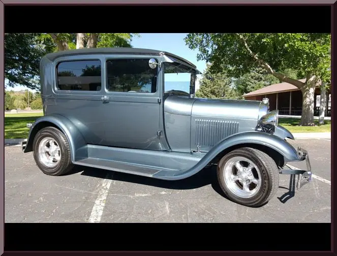 Antique car parked under sunny trees
