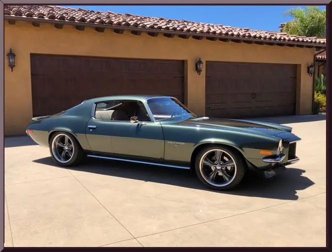 Classic green muscle car parked outside garage