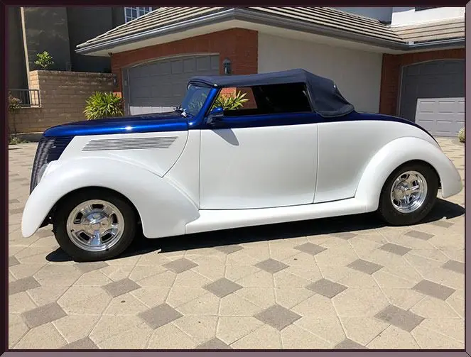 Classic blue and white roadster in driveway