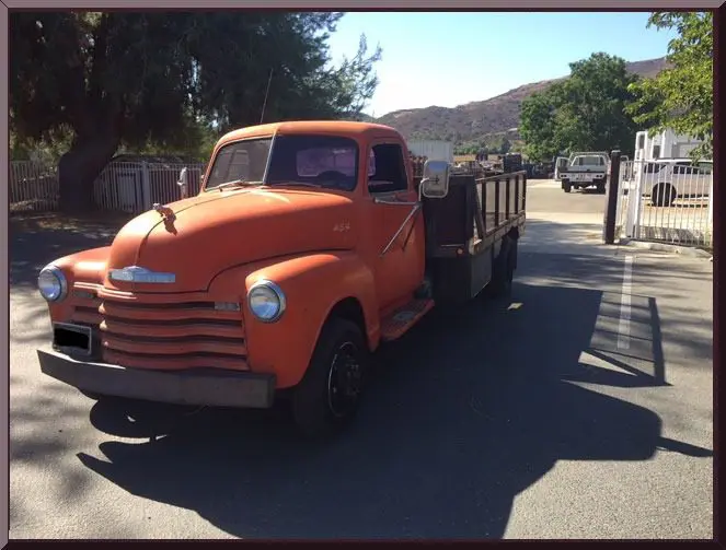 Orange vintage truck parked on sunny street