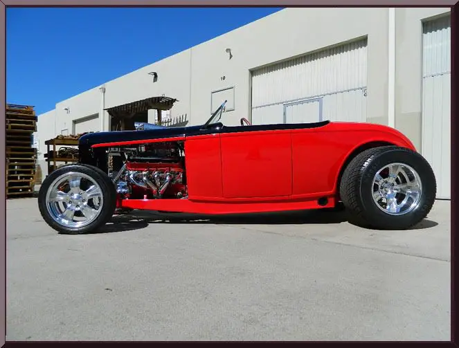 Red vintage hot rod parked outside building.