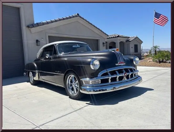 Classic black car parked by house