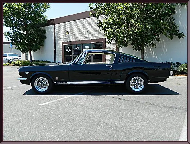 Classic black Mustang parked outside building