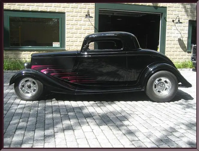 Classic black hot rod parked outside garage