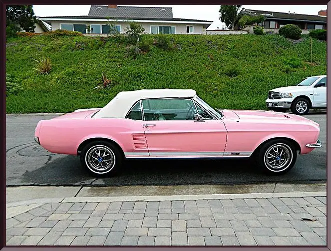 Pink vintage convertible car parked outdoors.