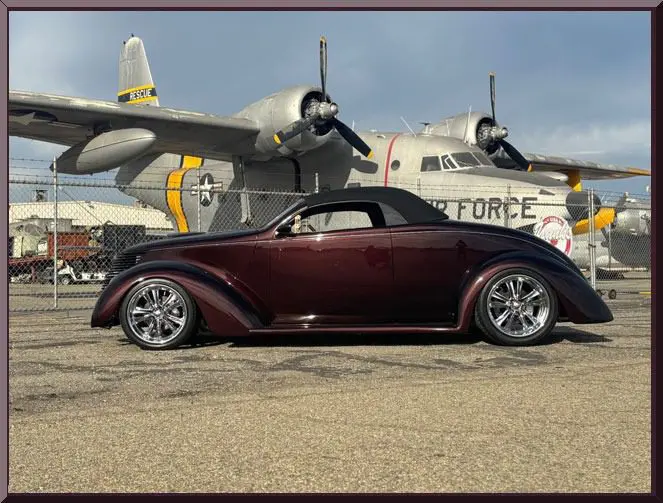 Classic car parked near vintage aircraft