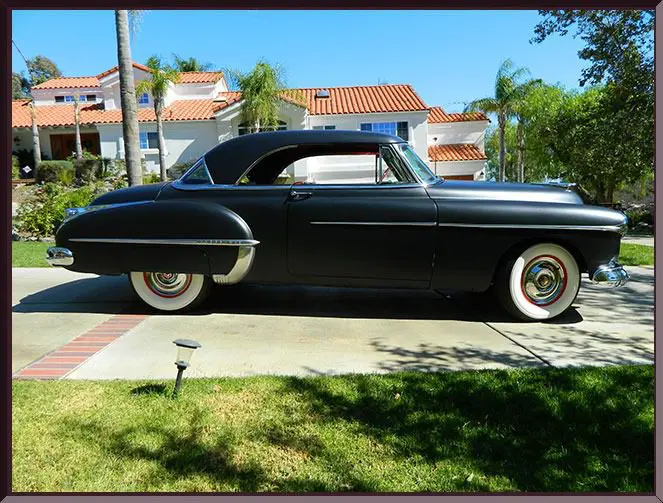 Classic black coupe parked in driveway