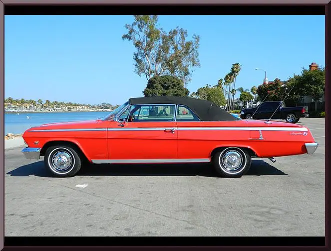 Red vintage convertible with black top by waterfront
