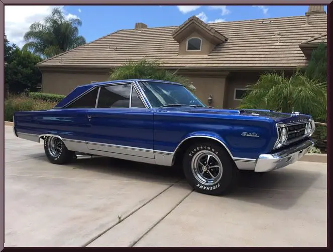 Classic blue muscle car parked outside house.