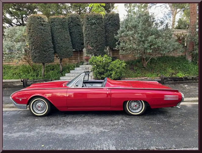 Vintage red car in front of hedges